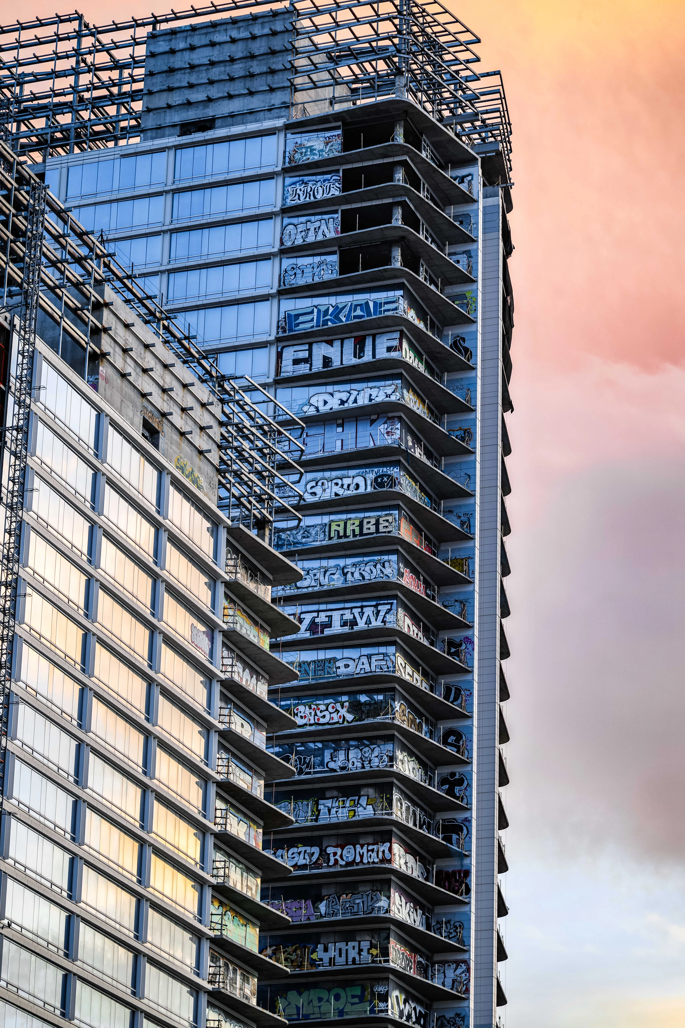 The exposed crown of an Oceanwide tower above blue glass and painted balconies